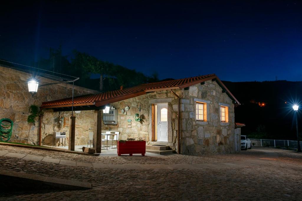 a stone building with a red bench outside at night at Casinha do Sabugueiro in Ponte de Lima