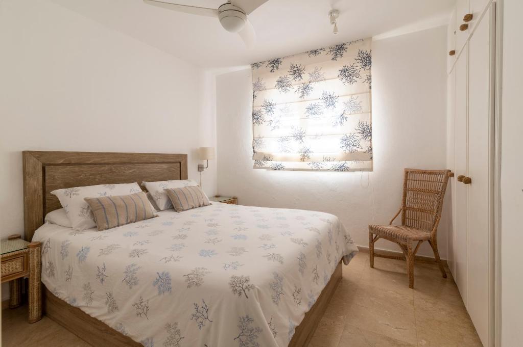 1 dormitorio con cama, ventana y silla en Apartamento junto a la playa en San Bartolomé