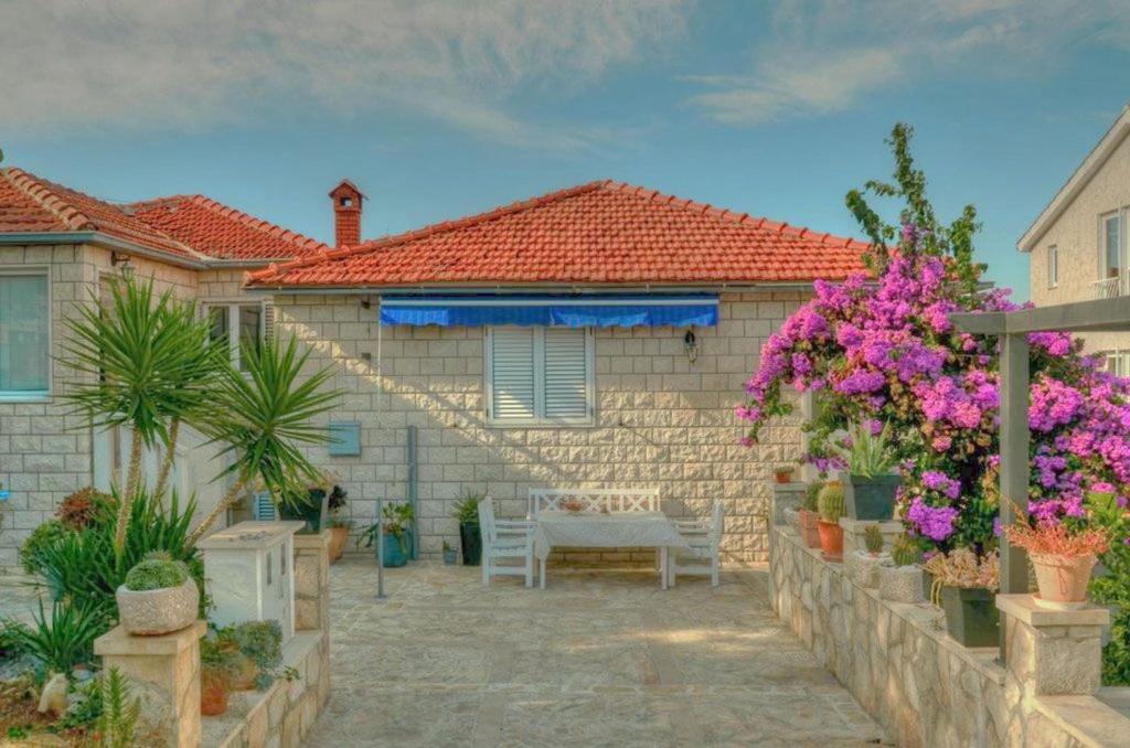 ein Haus mit einem Tisch und einigen Pflanzen und Blumen in der Unterkunft Apartments Ivanka in Supetar
