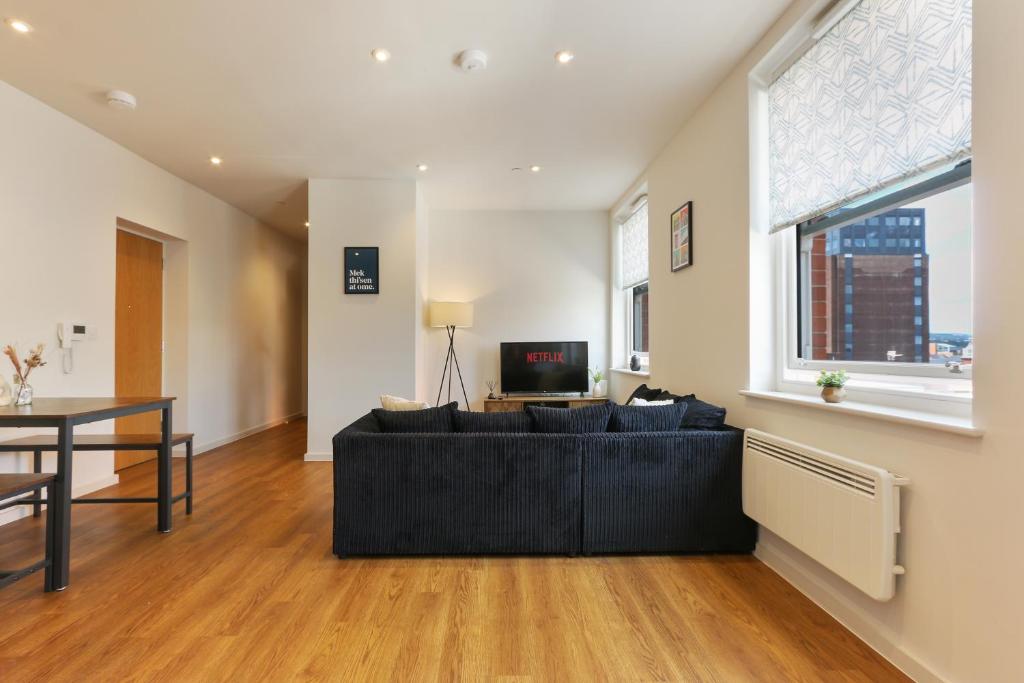 a living room with a black couch and a tv at Luxury Modern 2-Bed Apartment - City Centre, FREE Netflix, Pet Friendly in Sheffield