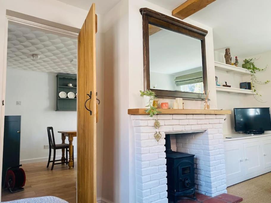 een woonkamer met een open haard en een spiegel bij The Town House in Aylsham