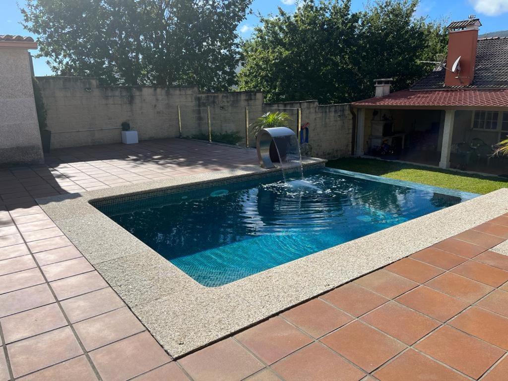 a swimming pool with a fountain in a yard at La Casa de las Ranas in Poio