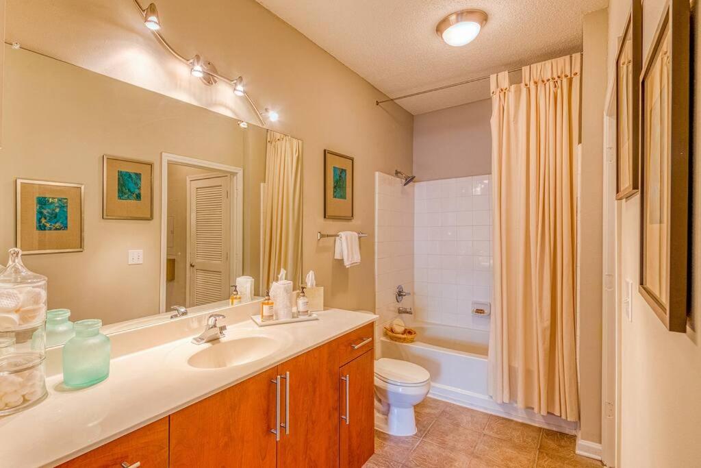 a bathroom with a sink and a toilet and a mirror at Luxury at Perimeter Gardens. in Dunwoody