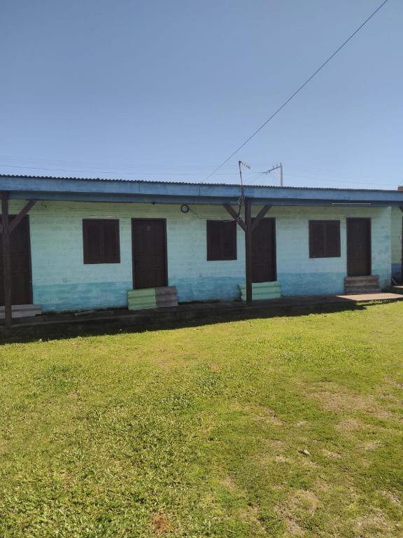 ein blaues Gebäude mit einem Grasfeld davor in der Unterkunft Pousada do bololo in Cidreira