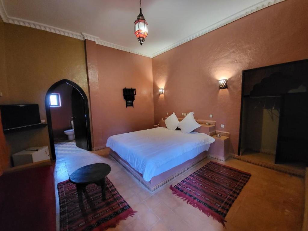een slaapkamer met een wit bed en een televisie bij hotel jnane la kasbah 