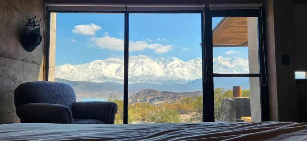 a bedroom with a view of mountains through a window at La Calma Ecolodge in Las Heras