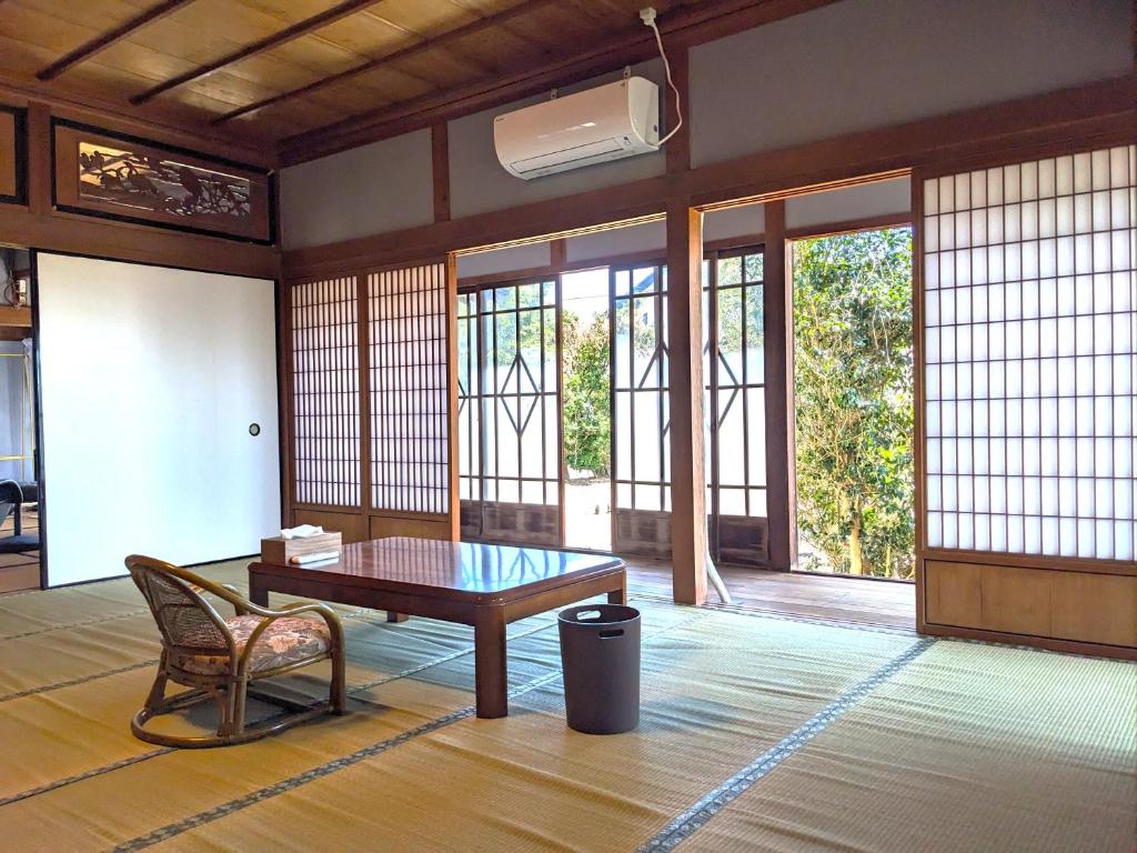 Habitación con mesa, silla y ventanas. en 和風ホテル鳴門家族連れにおすすめの和室でのんびり滞在できる宿, en Naruto