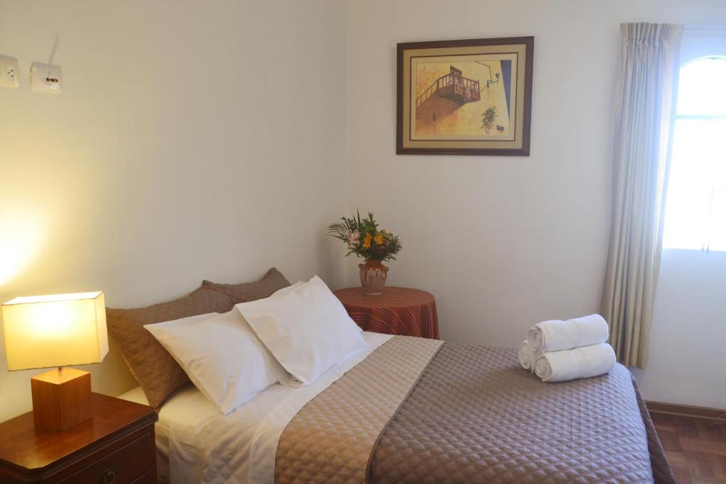 - une chambre avec un lit, une lampe et une fenêtre dans l'établissement Casa Rodas, à Lima