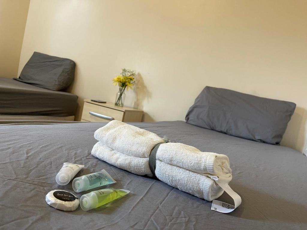 a towel on a bed with two bottles of soap at Stratford Guest House By Cosystays in London
