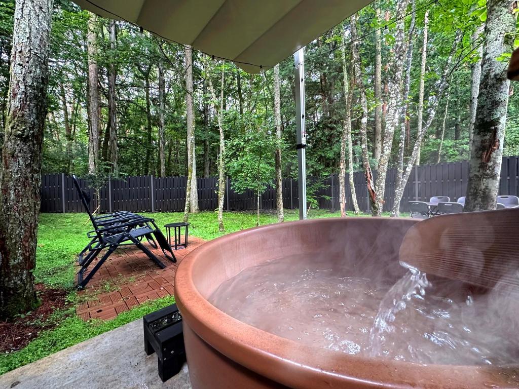 a large copper tub in a yard with a picnic table at Fuji Fumoto Forest Onsen ふじ ふもとの森温泉 in Fujikawaguchiko