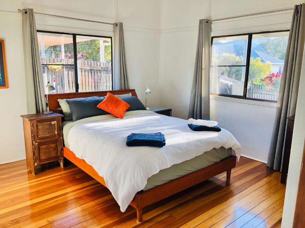 a bedroom with a bed and two windows at Jindy's Cottage Atherton in Atherton