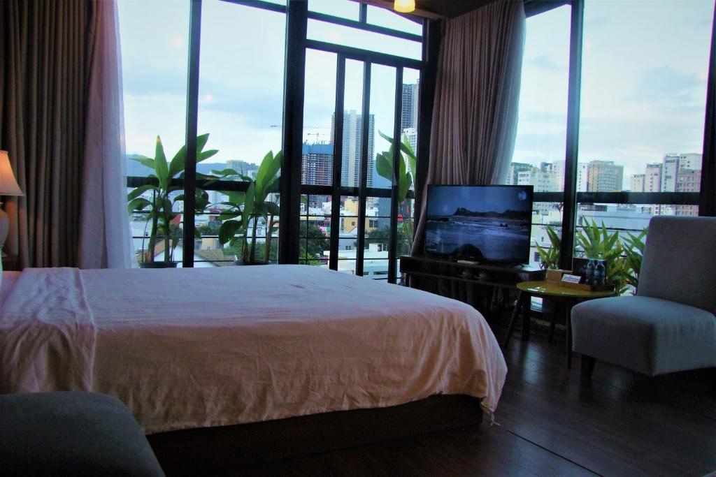 a hotel room with a bed and a tv and windows at Oasis Hotel & Apartment in Da Nang
