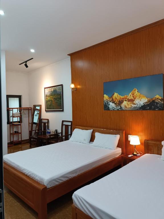 a hotel room with two beds and a desk at An Homestay & Hostel Motorbikes & Tours in Cao Bằng