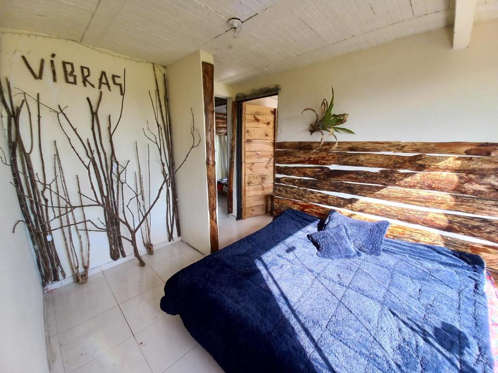 a bedroom with a blue bed with a wooden wall at Vibras Eco Hotel in Popayan