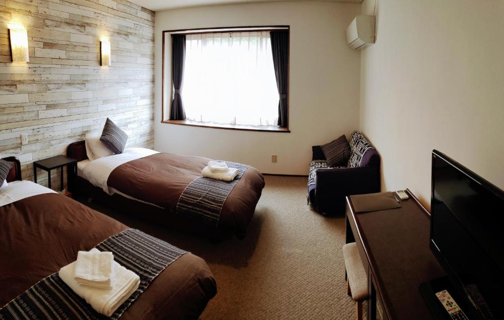 una camera d'albergo con due letti e una televisione di White Tree Lodge Madarao Tangram a Shinano