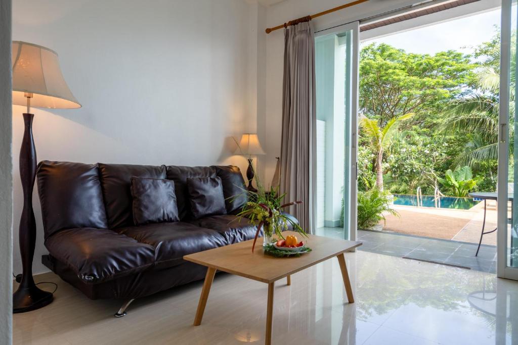 a living room with a leather couch and a table at 1Br Poolside Apartment, Long Beach, Lanta Sport Resort 109 in Ko Lanta