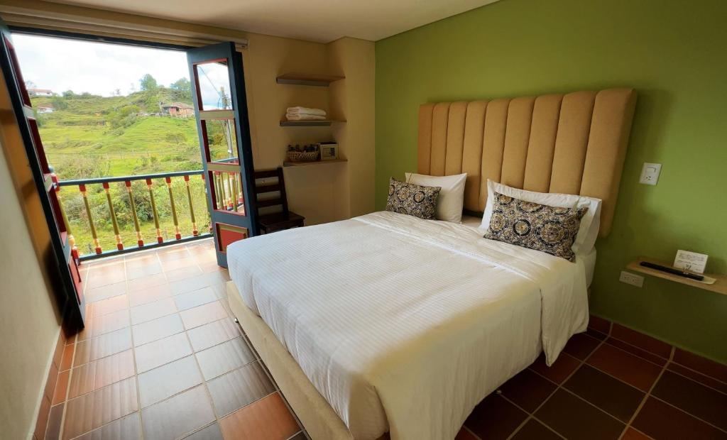 ein Schlafzimmer mit einem großen Bett und einem großen Fenster in der Unterkunft Ayenda Hotel Bambu Guatape in Guatapé