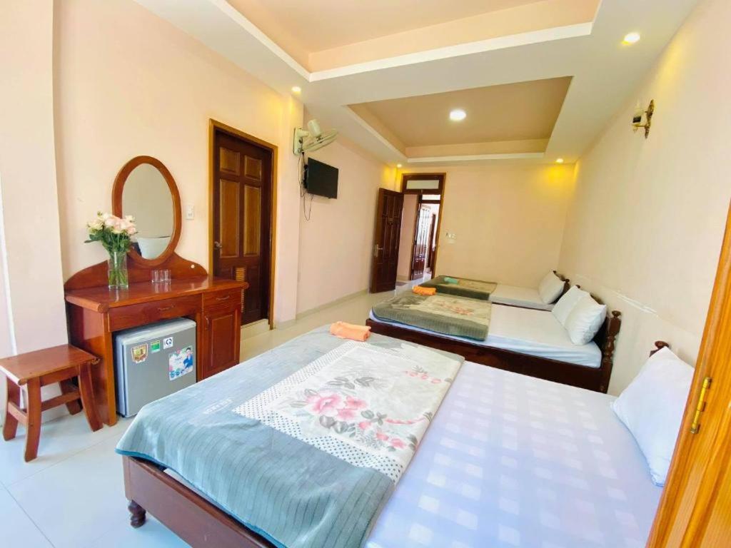 a bedroom with two beds and a desk and a mirror at Khách sạn Quang Vinh in Da Lat