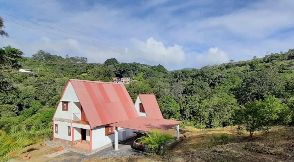 una pequeña casa con techo rojo en una colina en Cabaña Chalet La Lomita, en San Gil