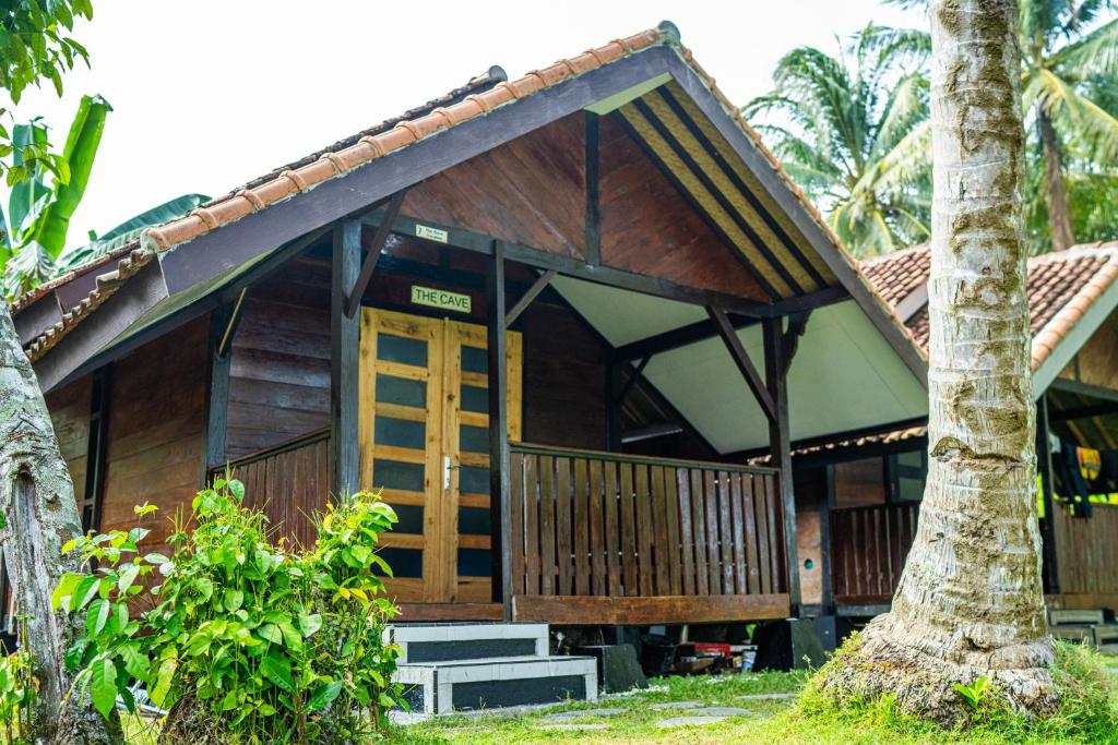 a wooden house with a palm tree in front of it at Sumatra Surf Resort in Biha