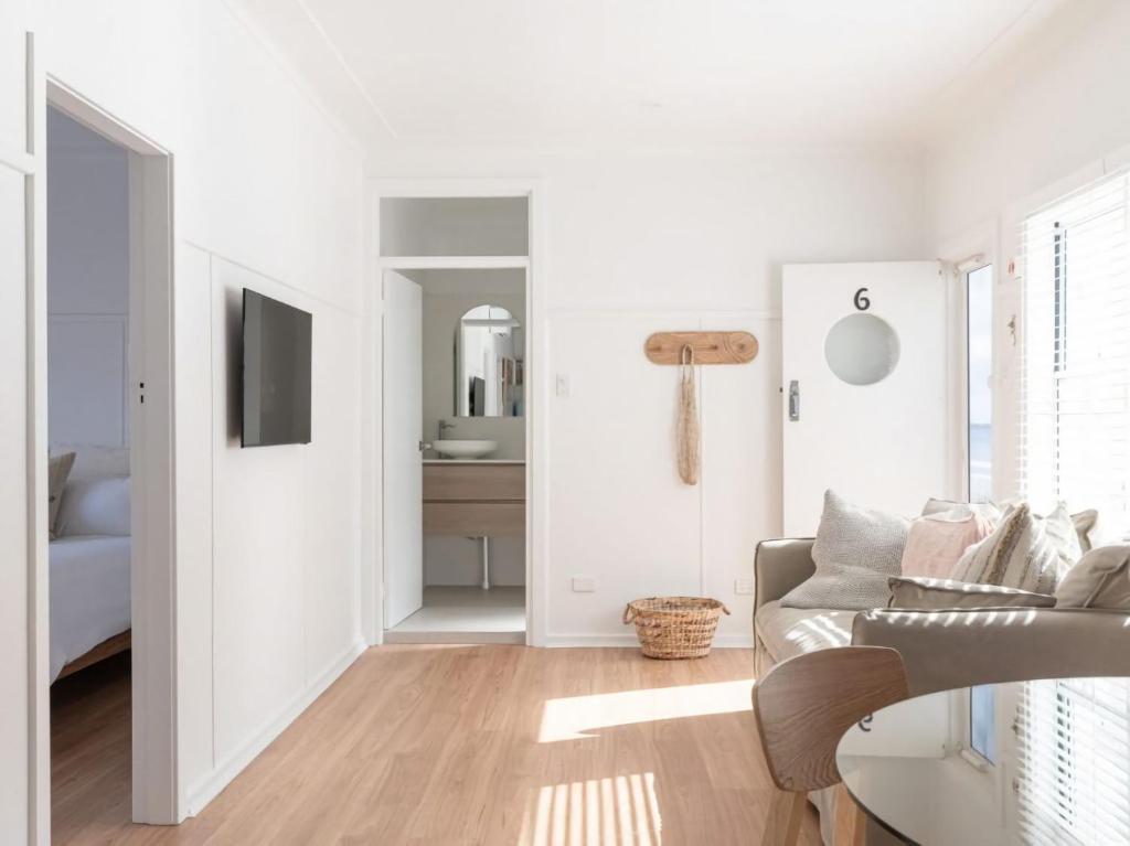 a white living room with a couch and a television at No 6 ShoalHaven in Shoal Bay