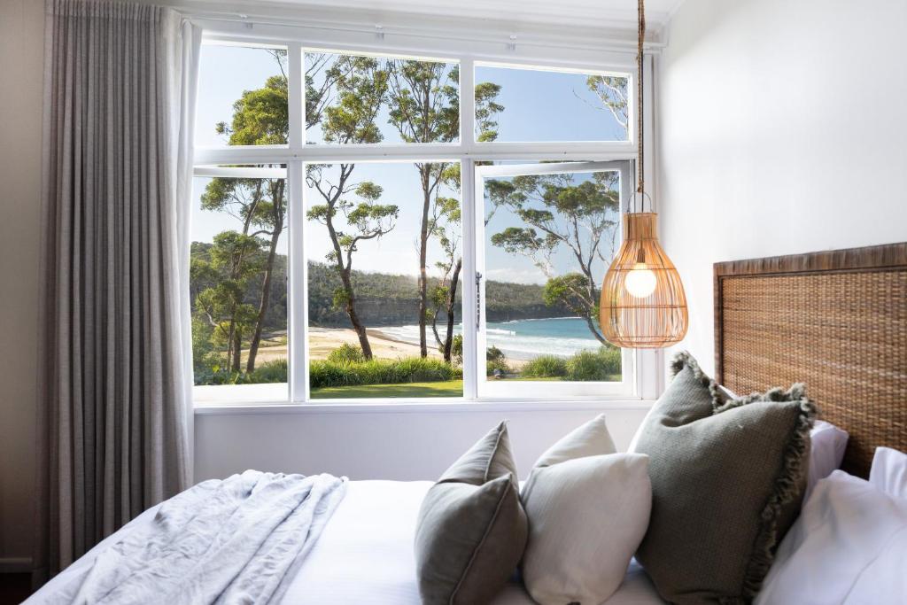 a bedroom with a window with a view of the ocean at Pebbly Beach Escape in East Lynne