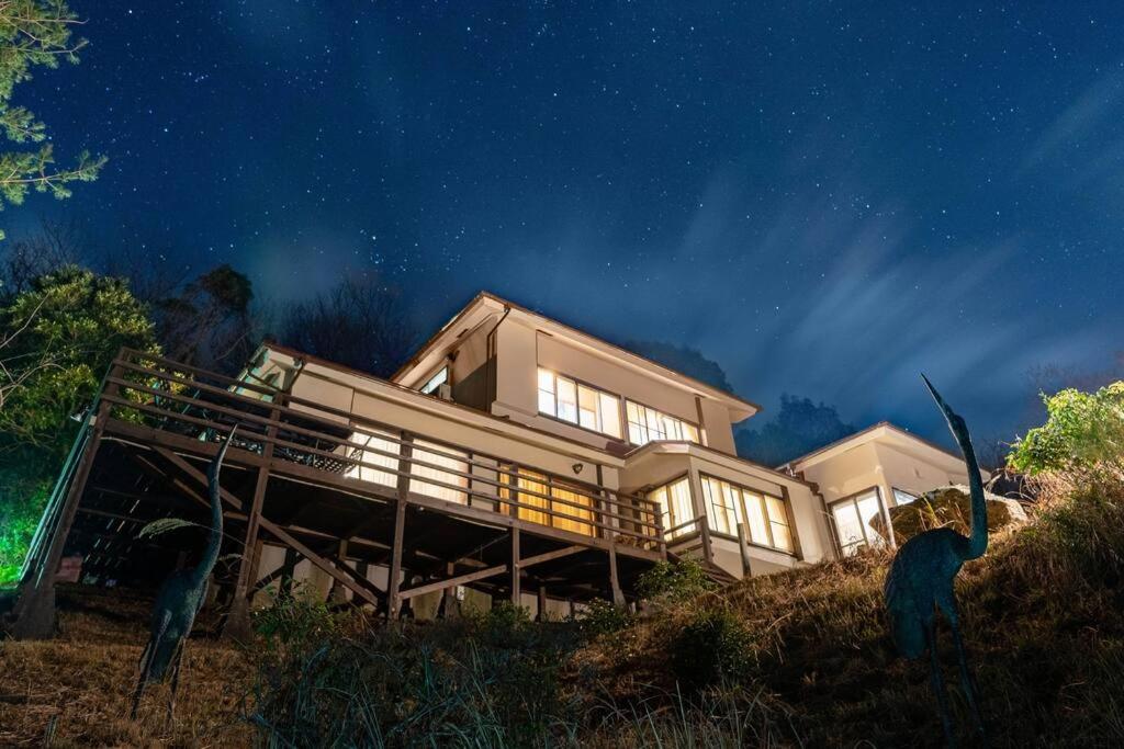 Ajiro的住宿－熱海網代 太平洋一望和式貸切一軒家 庭でバーベキュー，夜空坐在山顶的房子