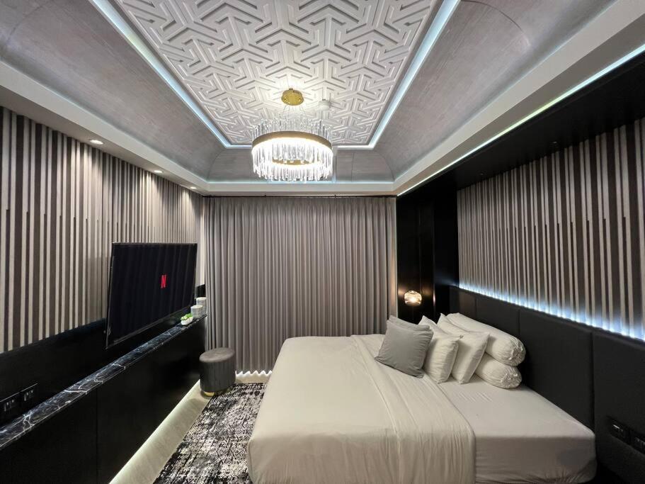a bedroom with a bed and a chandelier at Monochromic Studio Apartment by Kinasih Suites in Kejayan