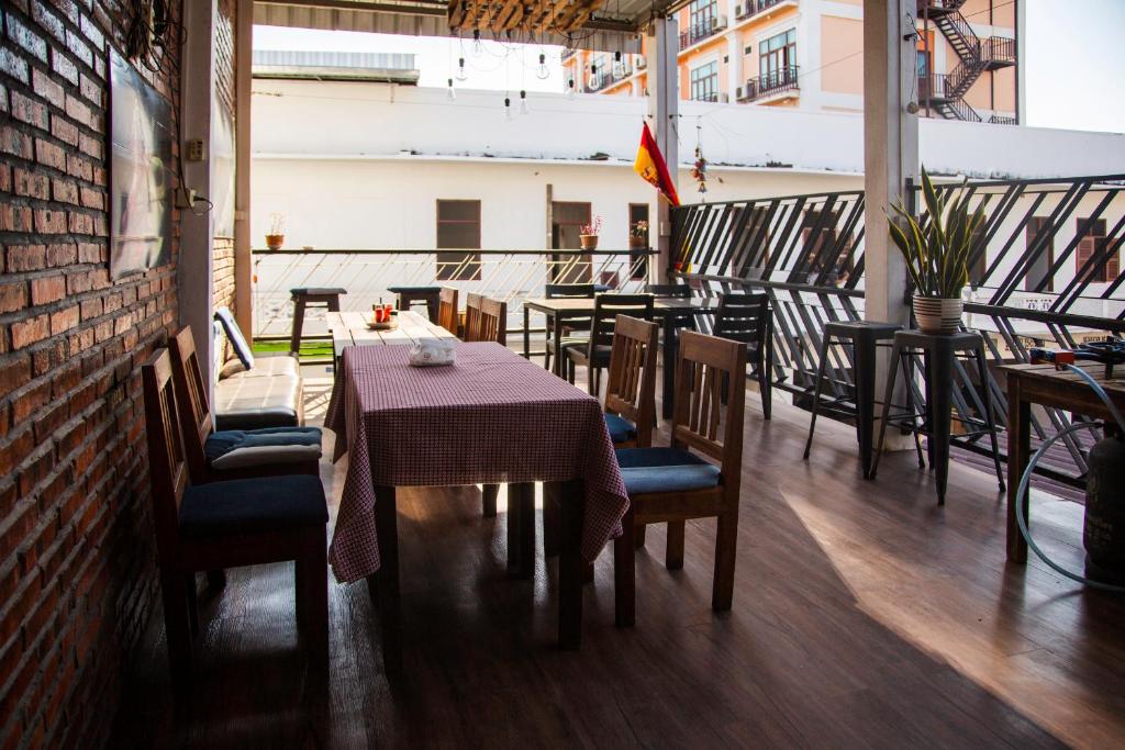 a dining room with tables and chairs and a brick wall at TT Hostel in Vientiane