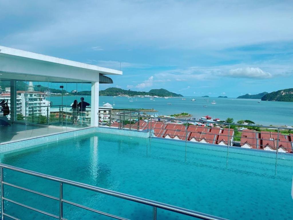 a swimming pool on top of a building with a view of the ocean at Bayu Apartment Services in Kuah
