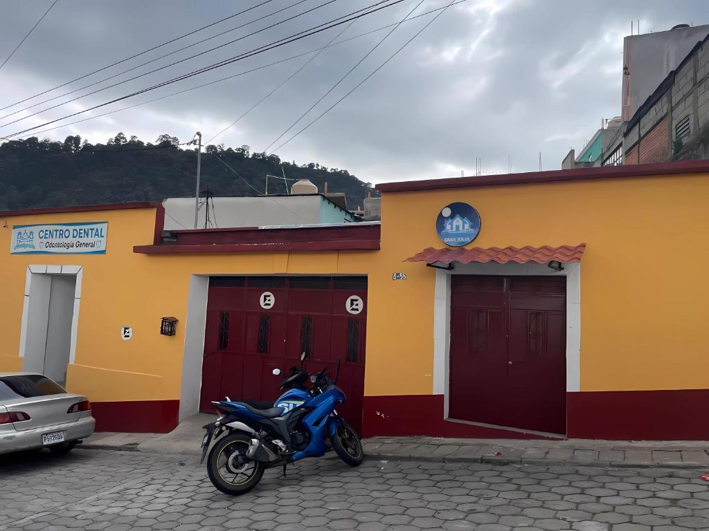Una motocicleta azul estacionada frente a un edificio en Casa Julia Xela en Quetzaltenango