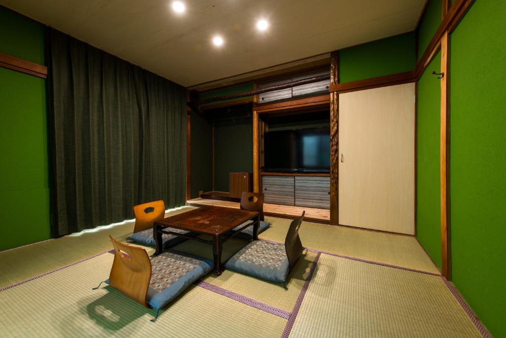 a living room with green walls and a table and chairs at 三津ミーツ in Mitsuhama