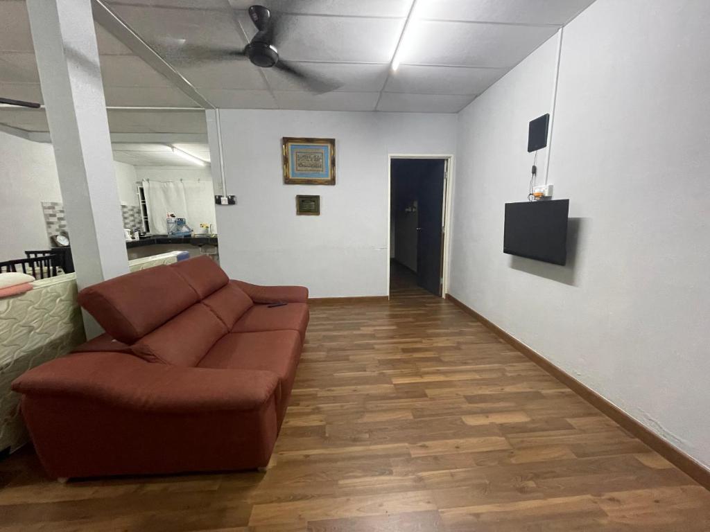 un soggiorno con divano marrone in una camera di ADEELA HOMESTAY @ BANDAR KUANTAN a Kuantan