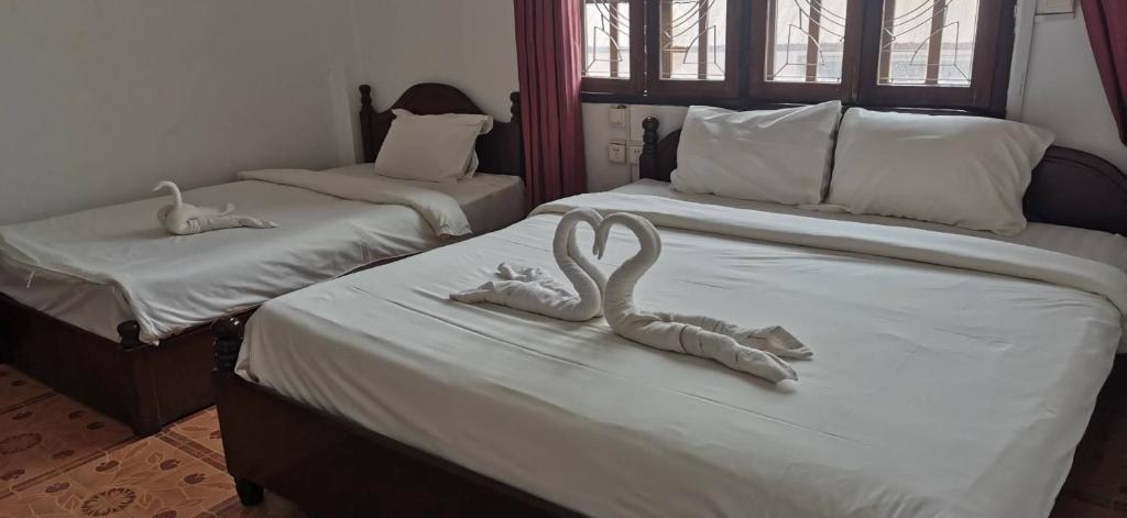 twee zwanen gemaakt van handdoeken op twee bedden bij 华泰酒店HUA TAI HOTEL in Vang Vieng