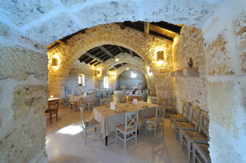una sala da pranzo con tavoli e sedie in un edificio in pietra di Masseria Triticum a Francavilla Fontana
