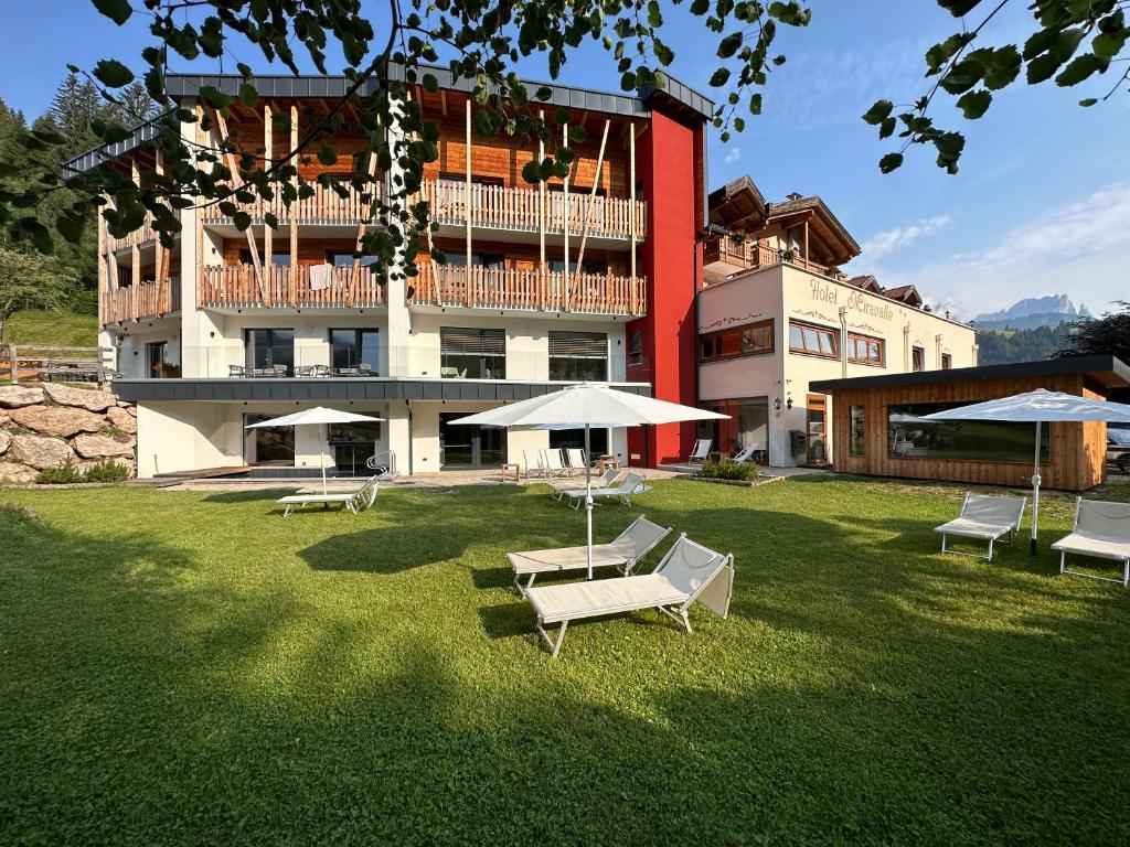 un bâtiment avec des tables et des parasols dans une cour dans l'établissement Hotel Miravalle, à Soraga