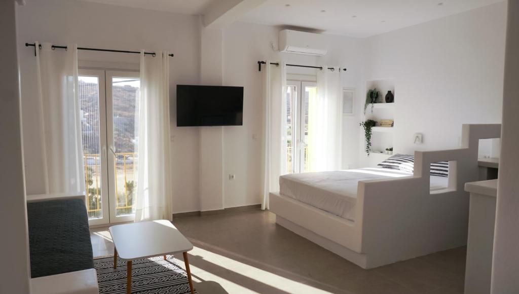 a white bedroom with a bed and a tv at ΟTTO apts in Loutrá