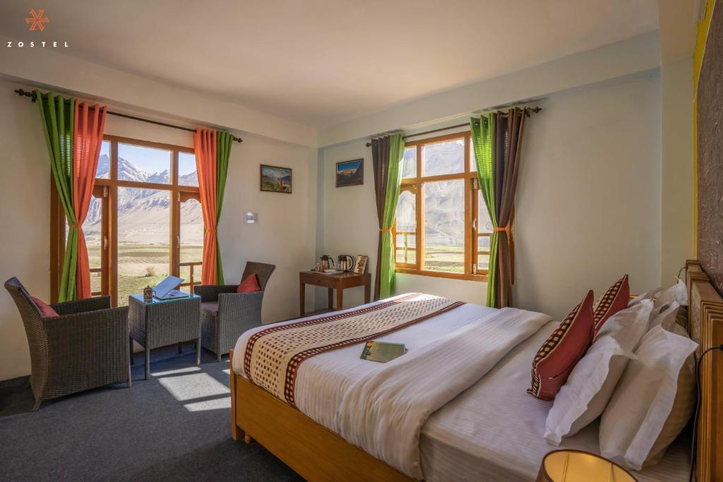 1 dormitorio con 1 cama, escritorio y ventanas en Zostel Spiti en Kaza
