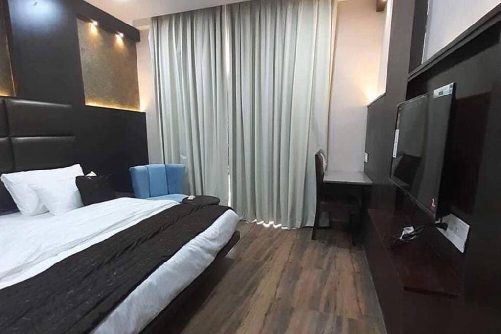 ein Hotelzimmer mit einem Bett und einem TV in der Unterkunft The Raas Mahal in Jaipur