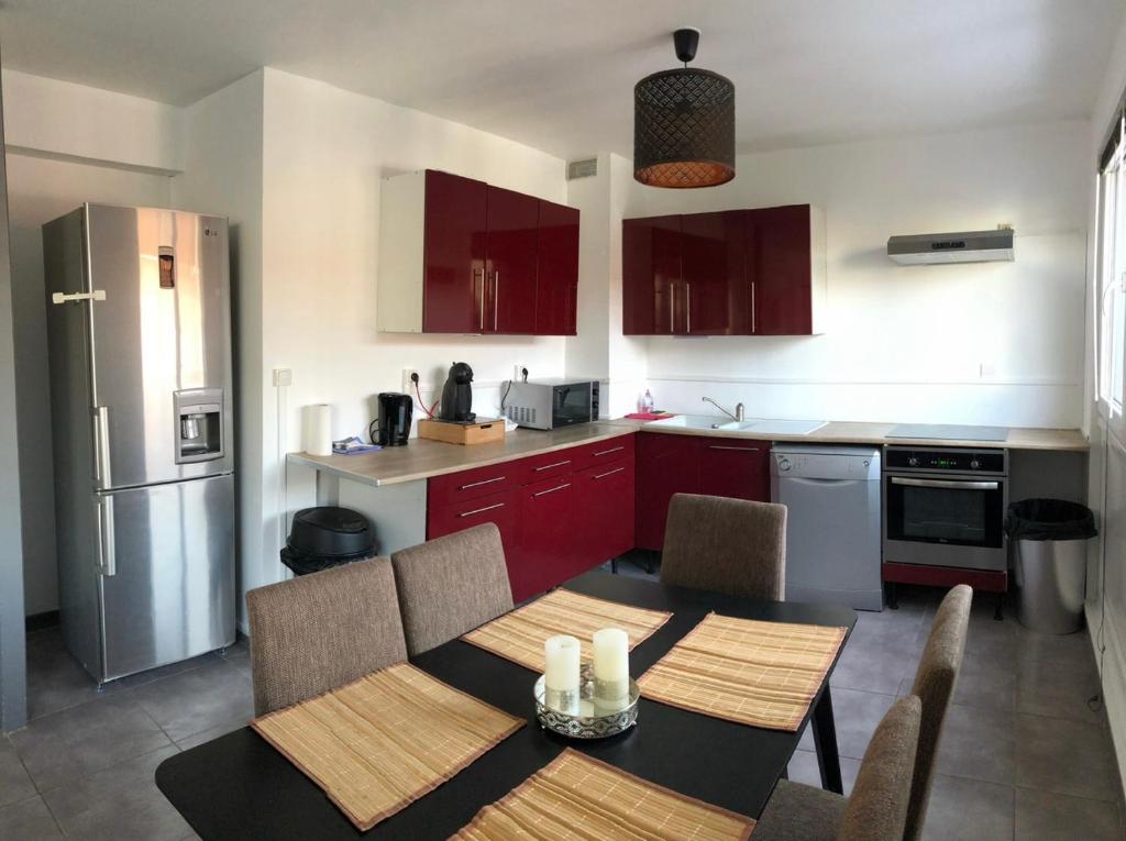 una cucina con armadi rossi, tavolo e sedie di Bel appartement cosy très calme avec parking privé a Templemars