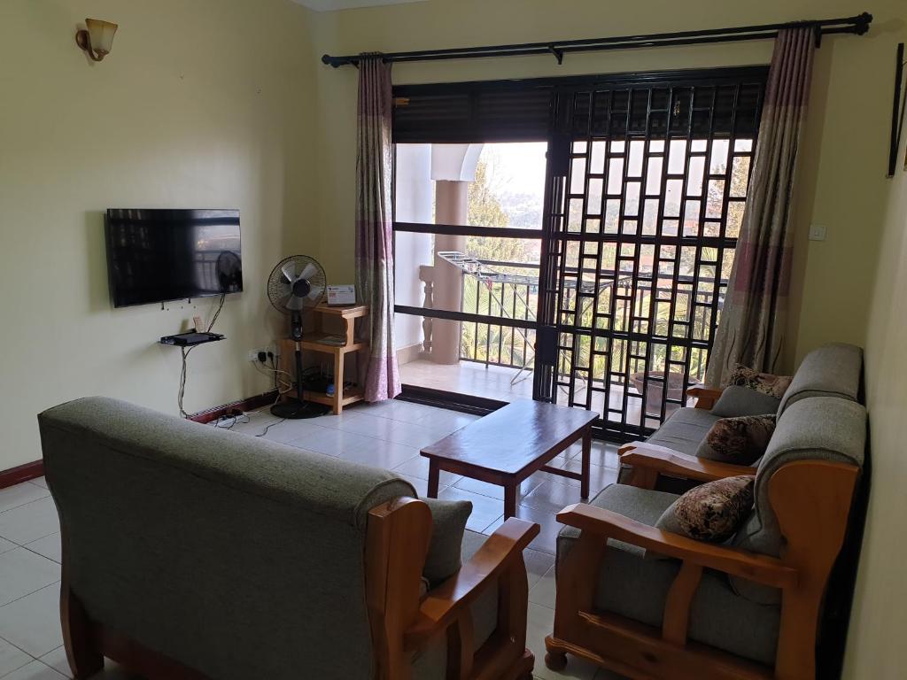 Sala de estar con 2 sofás, mesa y TV en 3-Bedroom Mbarara Apartment with Optional Farm Tour, en Mbarara