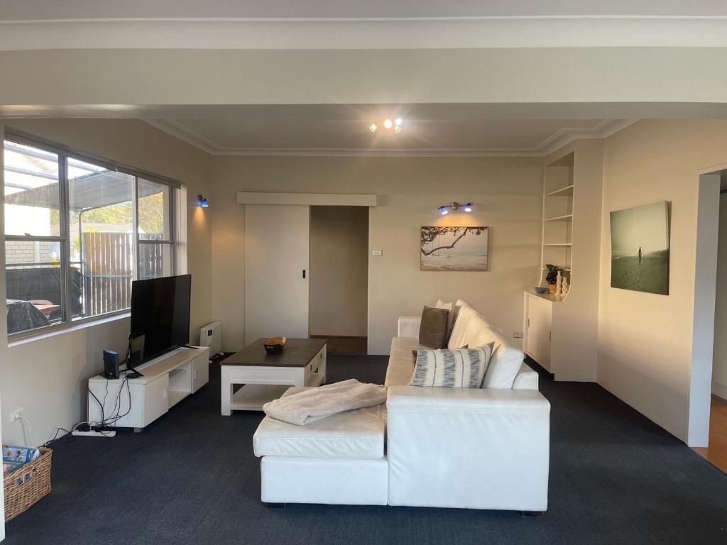 a living room with a white couch and a tv at Banyan spacious three bedroom pet friendly property with air con in Nelson Bay