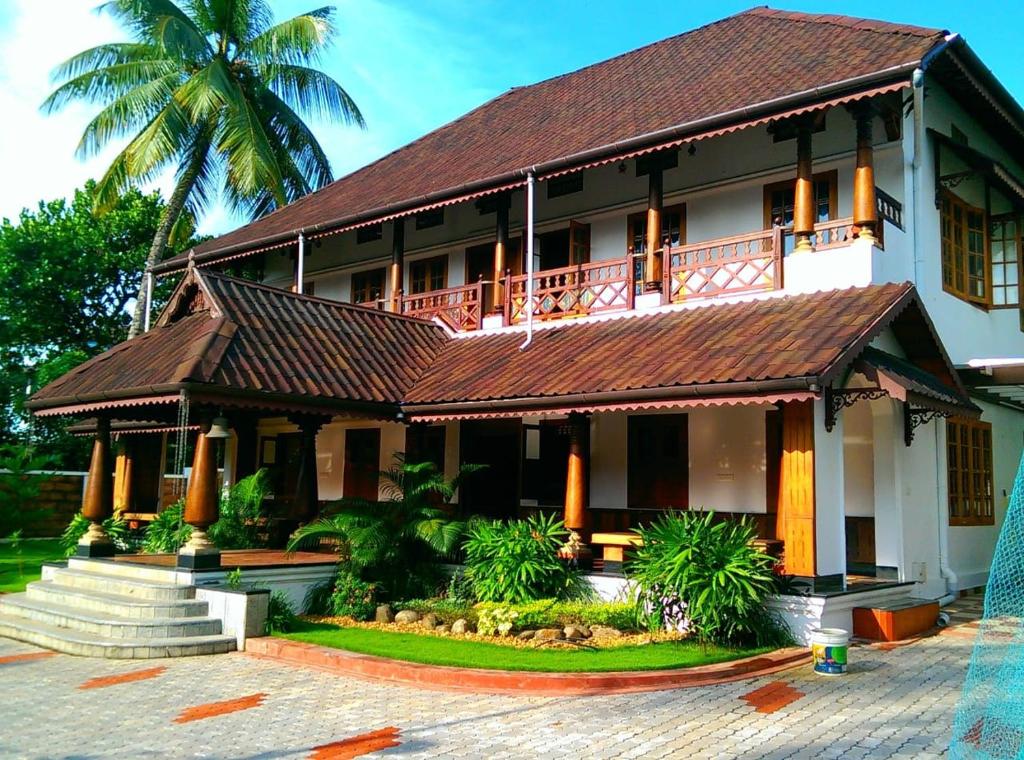 a building with a balcony and a palm tree at AZZA Heritage Home in Cochin