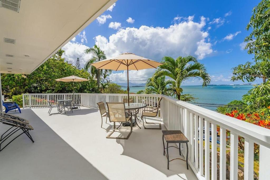 a balcony with tables and chairs and the ocean at @ Marbella Lane - Sunshine Seascape Ocean View in Kaneohe