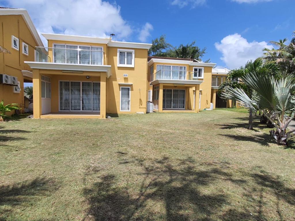 a large yellow house with a yard in front of it at Ocean villa in Palmar