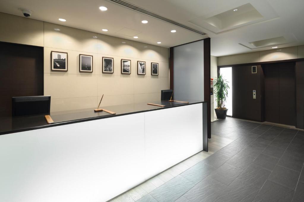 東京にあるホテルマイステイズ浜松町の受付カウンターと広告付きのオフィスロビー