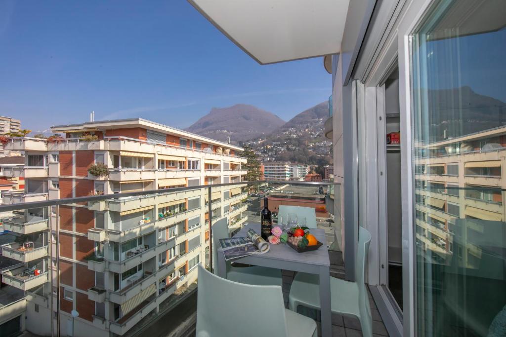 einen Balkon mit einem Tisch und Blick auf die Gebäude in der Unterkunft Sunrise House - Happy Rentals in Lugano