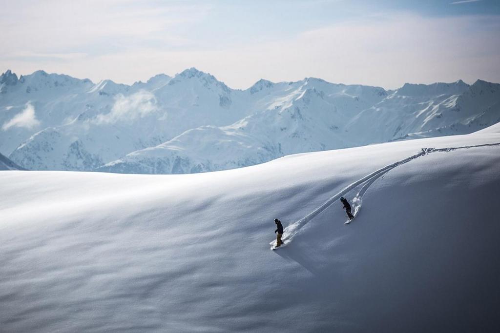 dos personas están esquiando por una montaña cubierta de nieve en Ski Arcs 1800 Ruitor, en Arc 1800