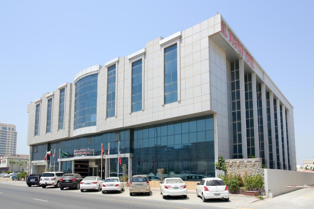a large building with cars parked in front of it at Al Bustan Hotel in Sharjah