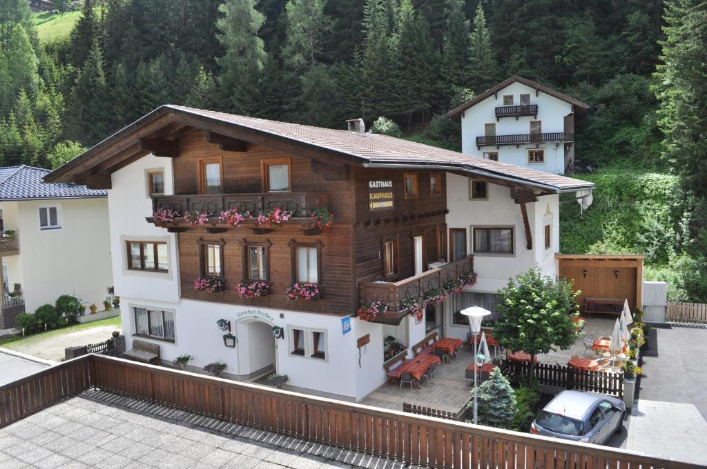 ein großes Holzhaus mit Balkon und Auto in der Unterkunft Gasthof Perfler in Außervillgraten